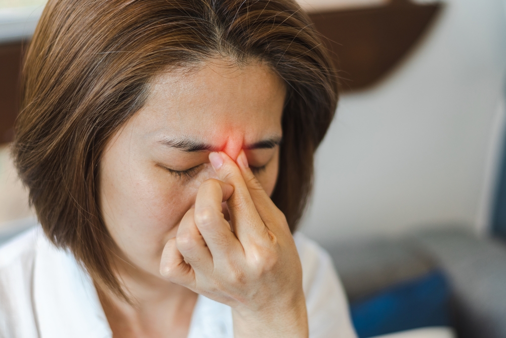 Woman suffering from sinus pain, pinching the bridge of her nose